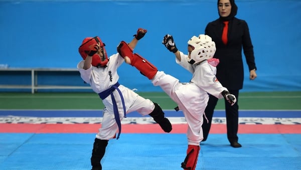 A referee watches girls fight, during an all women's karate competition