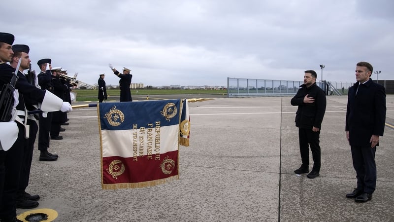 Volodymyr Zelensky and Emmanuel Macron listen as their respective national anthems are played