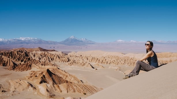 Woman sitting on a dune looking at the Atacama Desert