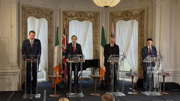 Jim O'Callaghan, Simon Harris and Hilarry Benn speak on a stage in Farmleigh