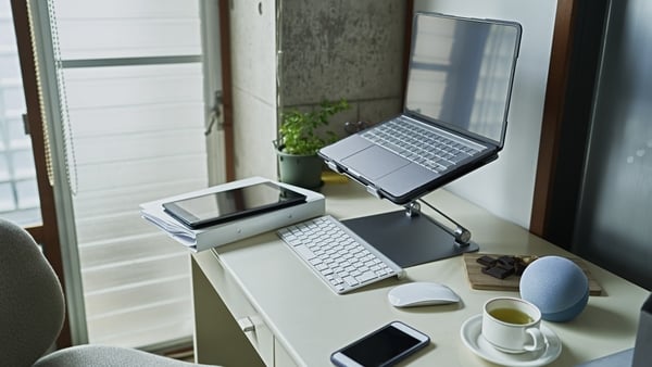 Photo shows a remote work desk with laptop, smart tablet and smart phone along with a cup of tea