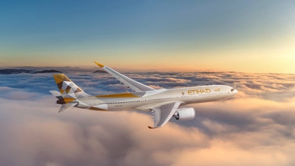 Image of an Airbus plane with the Etihad logo flying over clouds