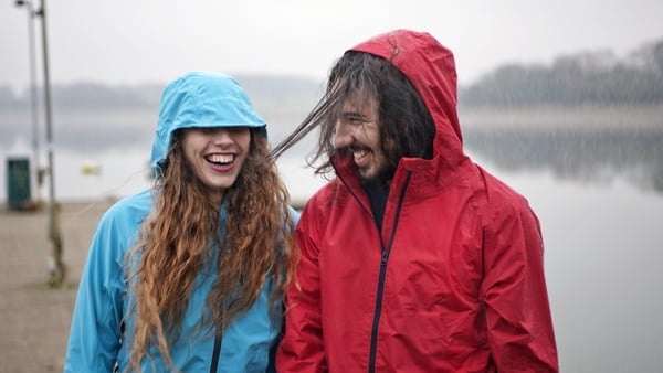 A couple standing in raincoats smiling