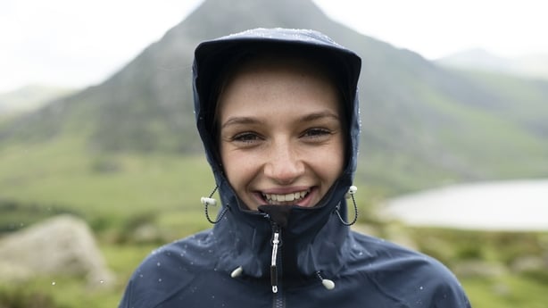 Woman smiling in rain jacket while hiking
