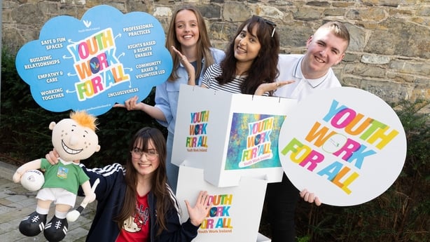 Four young people hold signs with text about Youth Work For All