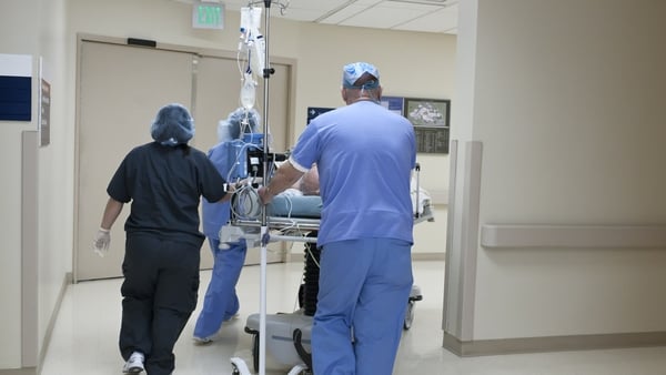 People in hospital scrubs push a trolley