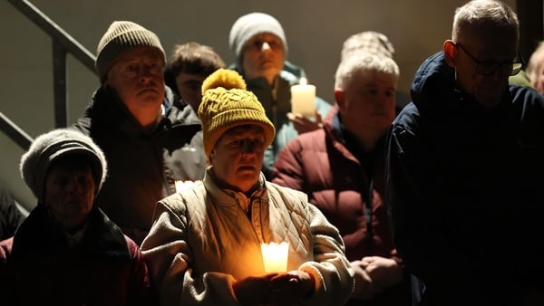 People hold candles at a vigil