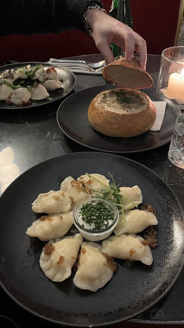 A plate of pierogi and a bowl of soup in a bread bowl