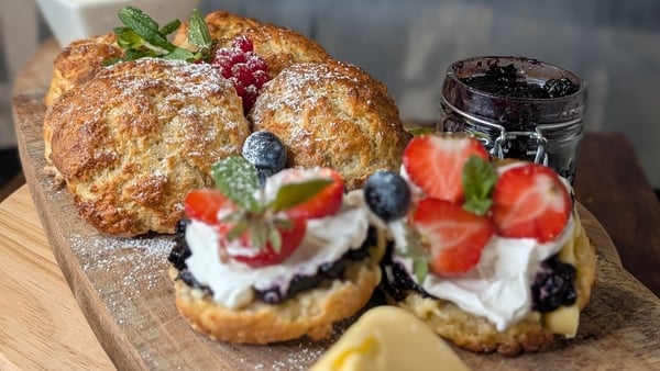 A board of homemade scones with cream and berries