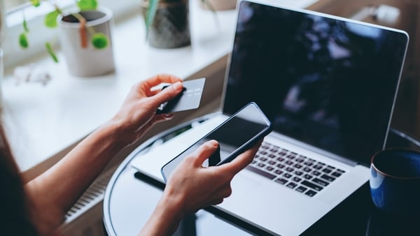 Woman shopping online with laptop, entering credit card details to make mobile payment online at home