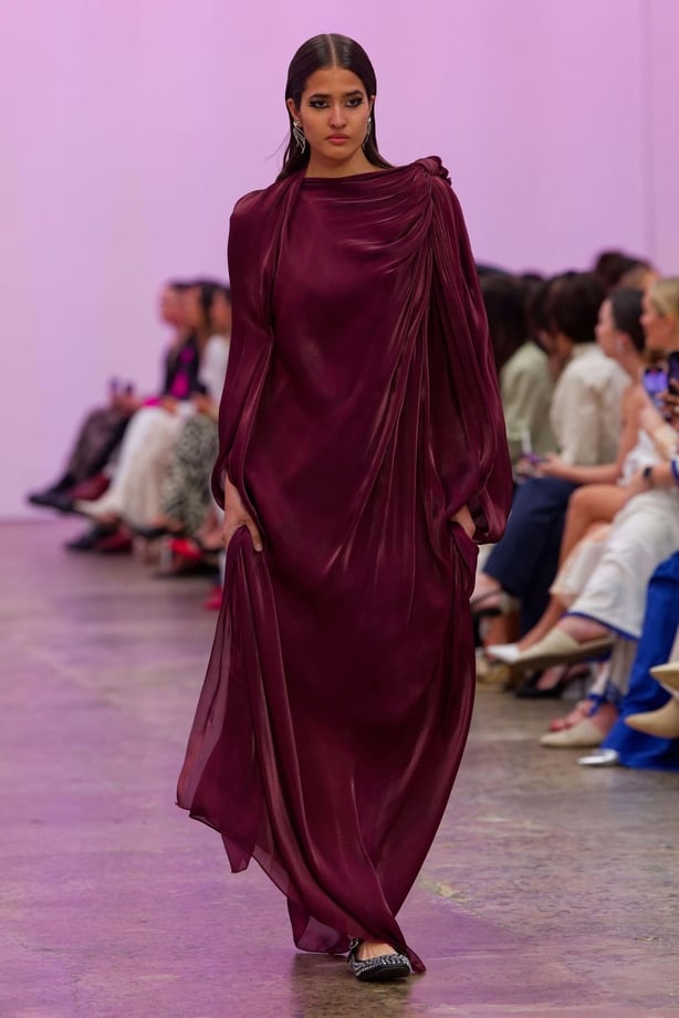 A model walking a runway in a long draped dress