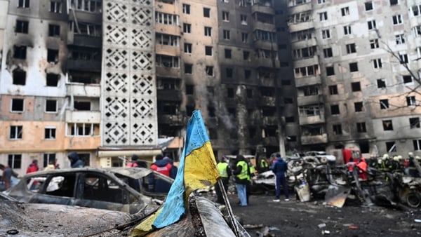 A Ukrainian flag is seen attached to a burned car at the site of a heavily damaged residential building following Russian air strike in the city of Ternopil