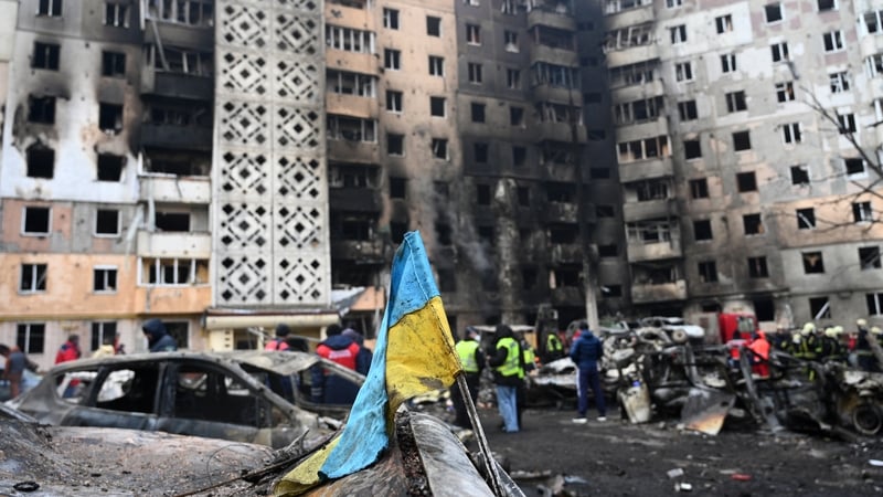 A Ukrainian flag is seen attached to a burned car at the site of a heavily damaged residential building following Russian airstrike