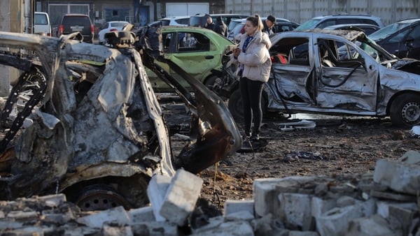 People inspect destroyed cars in the parking lot of a car service station following an air attack in Odesa on November 21, 2025,