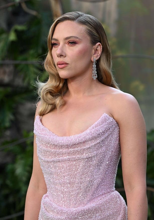 Scarlett Johansson wearing a purple deaded gown with her hair styled into loose waves