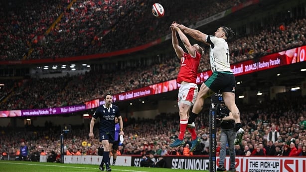 22 February 2025; James Lowe of Ireland out jumps Blair Murray of Wales to keep the ball in play, and assist his side's second try scored by teammate Jamie Osborne, not pictured, during the Guinness Six Nations Rugby Championship match between Wales and Ireland at the Principality Stadium in Cardiff