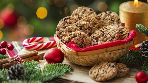 Chocolate chips cookies in a basket on decorated table near the Christmas tree. 
