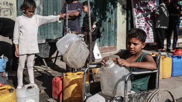 GAZA CITY, GAZA - NOVEMBER 22: Palestinians fill containers with water from a storage tank set up by the municipality and carry it back to their living areas at Nuseirat Camp as despite the cease-fire the water crisis continues due to the severe damage to infrastructure caused by Israeli attacks in 