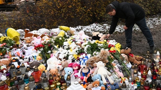 A man lays a toy at a memorial