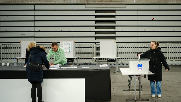 A voter registers to vote as other casts a ballot at a polling station during a referendum on whether a law legalising assisted dying will be enforced or suspended, in Ljubljana