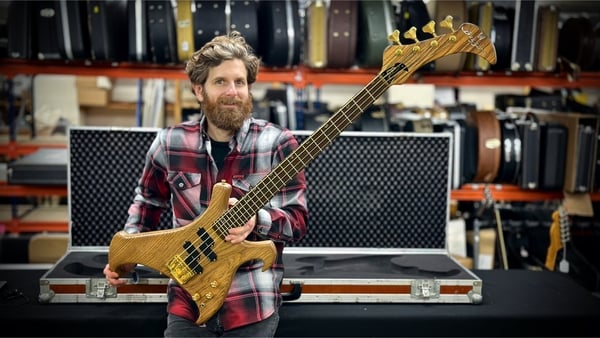 Auctioneer Luke Hobbs holding the Warwick Buzzard bass guitar
