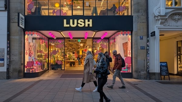 The storefront of a Lush cosmetics store with a logo, pink lights, and arched windows