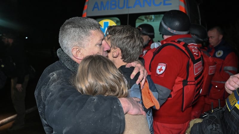 A man embraces his children in front of an emergency vehicle at the site of a Russian drone strike in Kharkiv