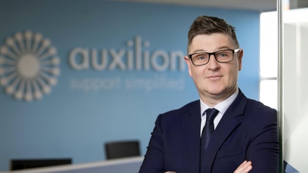 Picture of a business man in a suit with the Auxilion logo in the background