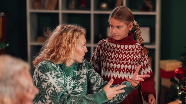Family members wearing festive christmas sweaters gathering around the table, enjoying dinner while engaging in a lively argument