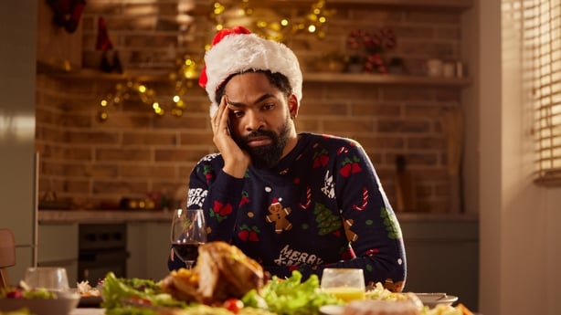 Sad African American man sitting alone during lunch on New Year at dining table.
