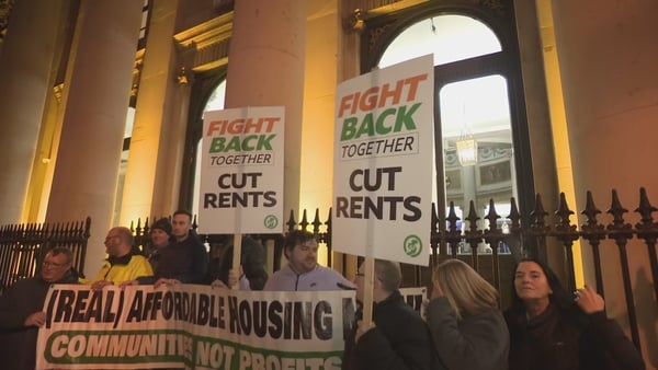Protesters outside City Hall raise banners at night time