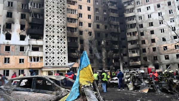 A Ukrainian flag is seen attached to a burned car at the site of a heavily damaged residential building following Russian air strike in the city of Ternopil
