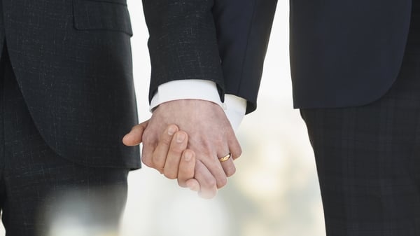 Two grooms holding hands at a wedding