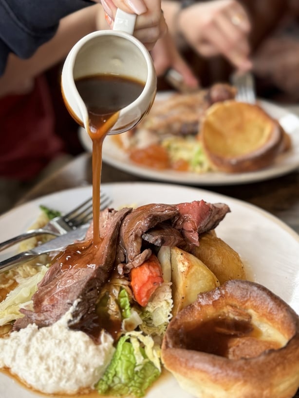 Stock photo of a traditional Sunday dinner featuring succulent roast beef, cooked to perfection and served with golden, crispy roast potatoes. Accompanied by fluffy Yorkshire puddings and a generous drizzle of rich gravy, this hearty meal is complemented by vibrant steamed cabbage and tender carrots
