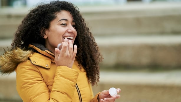 Woman putting on lip protection in the street