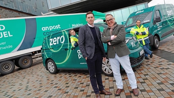 Image of green An Post electric vehicles with An Post's David McRedmond and Owen Keogh