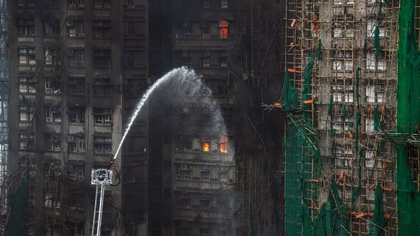 Firefighters use a hose to extinguish the smouldering residential building in Hong Kong.