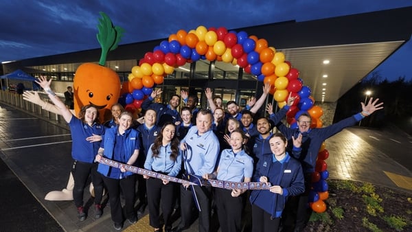 Aldi staff pose outside a new store in with a balloon arch in the background