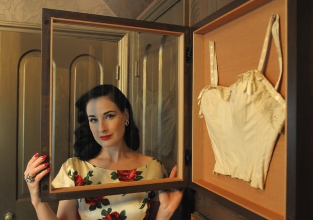 Dita Von Teese poses with her collection of pin-up art and brooches, as well as celebrity "artifacts" in her home in Los Angeles. One of her favorite pieces in her collection is this Betty Grable corset. (Photo by Axel Koester/Corbis via Getty Images)