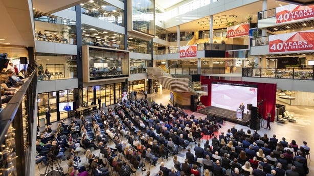 Image of Microsoft Ireland's headquarters with employees listening to a speaker on a stage