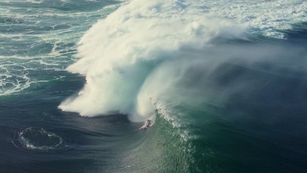 A surfer surfing through a massive swell wave.