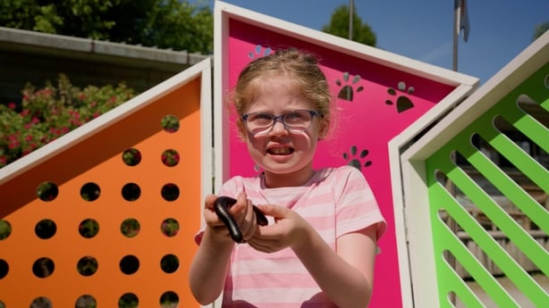 A young girl in a stripey t shirt holds a giant millepede