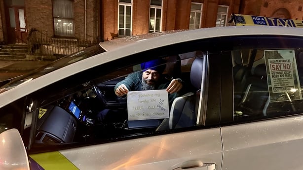 A Dublin taxi driver holds up a sign from his car during uber fixed fair protest 