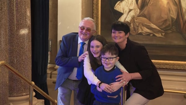 Two adults and 2 kids embrace and smile for the camera at an event.