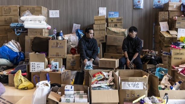 People sit amongst supplies at an evacuation centre near residential buildings damaged by fire in Hong Kong.