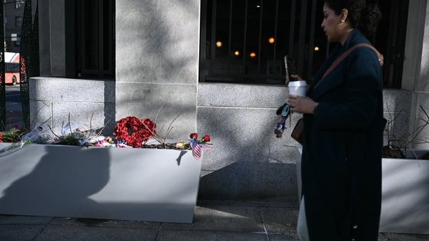 A woman walks past a makeshift memorial in honoring the two National Guard service members who were shot near the Farragut West Metro Station in Washington, DC on November 28, 2025, two days after a shooting killed one National Guard member and critically wounded another. Two National Guard troops w