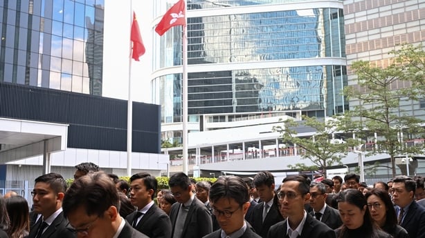 People observe a minute of silence for victims of a burning building in Hong Kong