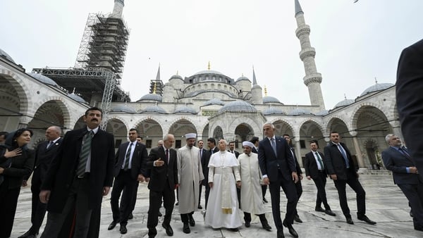 Pope Leo XIV at the centre of a group of people being led around a mosque