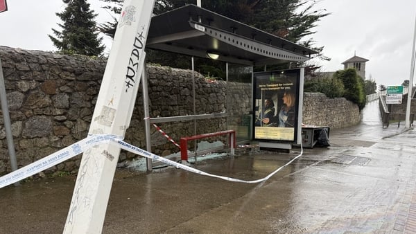 a garda tape is seen attached to a lamppost near a bus stop