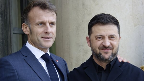 Emmanuel Macron (L) places his hand on the shoulder of Volodymyr Zelensky as they pose for a photograph